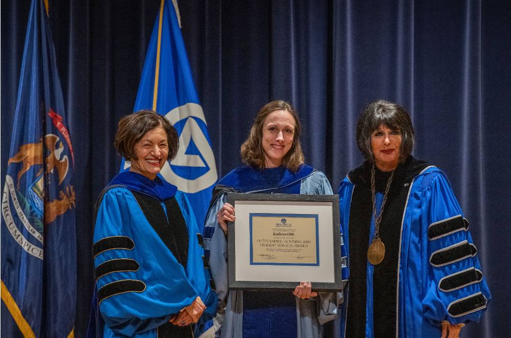 Provost Mili and President Mantella smile for picture with woman holding certificate